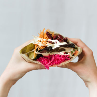 Closeup Shot Of Hands Holding Vegetarian Shawarma With Red Beans, And Pickles Wrapped In Pita Bread Closeup Shot Of Hands Holding Vegetarian Shawarma With Red Beans, And Pickles Wrapped In Pita Bread